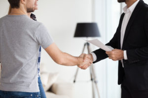 Young couple shaking hands with a landlord over a Real Estate Deal as tenants